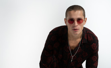 Obraz premium Half length portrait of cheerful sexy man in red sun glasses, wearing trendy black shirt, looking at the camera, isolated over white background