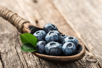 Blueberries in wooden spoon on old wood table. Healthy eating and nutrition concept.