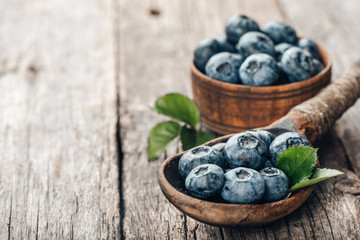 Blueberries in wooden spoon on old wood table. Healthy eating and nutrition concept.