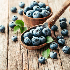 Blueberries in wooden spoon on old wood table. Healthy eating and nutrition concept.