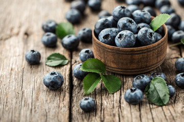 Freshly picked blueberries in wooden bowl on wooden background. Healthy eating and nutrition.