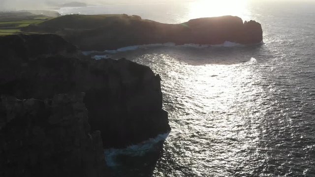 Aerial Drone Flyover grass to sea Azores Portugal sunset on coast of sea
