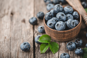 Freshly picked blueberries in wooden bowl on wooden background. Healthy eating and nutrition.