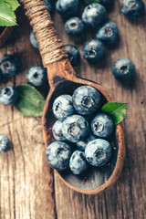 Blueberries in wooden spoon on old wood table. Healthy eating and nutrition concept.