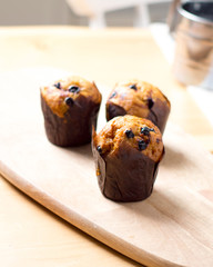 Freshly baked muffins with raisins on wooden board