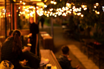 The atmosphere of a cozy relaxed mood, an evening meeting of young people in a coffee shop, blurred...
