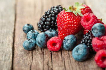 Fresh Summer Berries mix with Strawberry, Raspberry, Red currant, Blueberry and Blackberry on wood background.