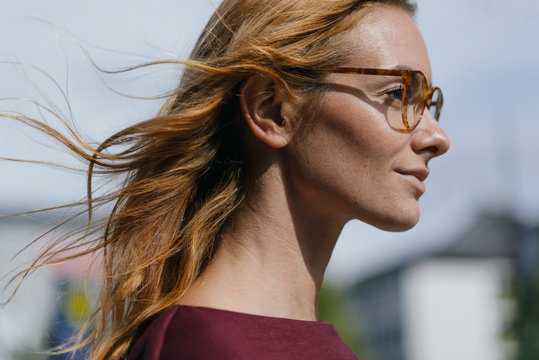 Profile of young woman with glasses and windswept hair