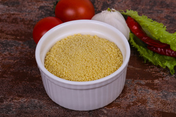 Raw couscous in the bowl served salad leaves, tomato and pepper