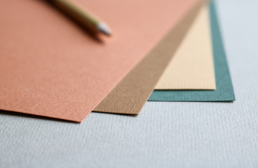 Close up of a stack of uncoated fine art paper in different warm brown and green colours and a...