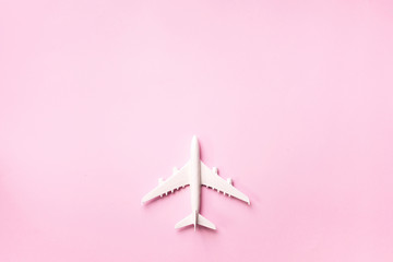 Creative layout. Top view of white model plane, airplane toy on pink pastel background. Flat lay with copy space. Trip or travel banner