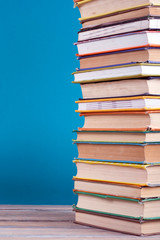 Book stacking. Open hardback books on wooden table and blue background. Back to school. Copy space for ad text