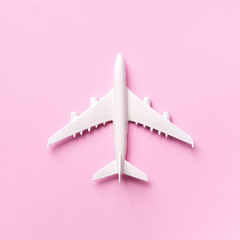 Travel, vacation concept. White model airplane on pastel pink color background with copy space. Top view. Flat lay. Minimal style design. Square crop