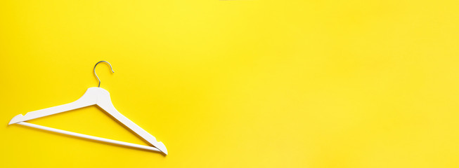 Top view of white clothes hangers on yellow background with copy space. Flat lay. Minimalism style. Creative layout. Fashion, store sale, shopping concept. Banner for feminine blog