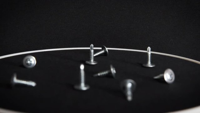 Screws spinning on a black background. Self-tapping screws are spinning on a black background.