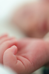 Hands of sleeping newborn baby. Face in shallow depth of field.