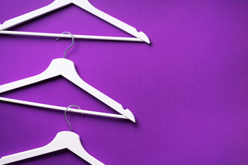 White clothes hangers on violet background with copy space. Flat lay. Top view. Minimalism style. Creative layout. Fashion, store sale, shopping concept. Banner for feminine blog