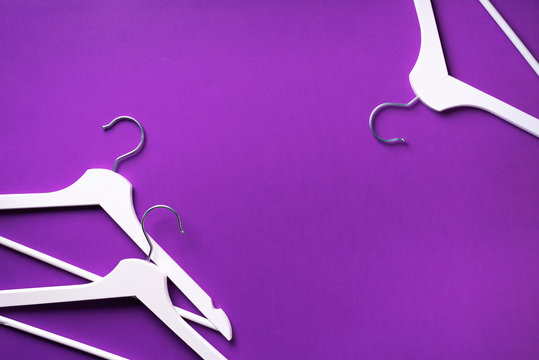 Top view of white clothes hangers on violet background with copy space. Flat lay. Minimalism style. Creative layout. Fashion, store sale, shopping concept. Banner for feminine blog