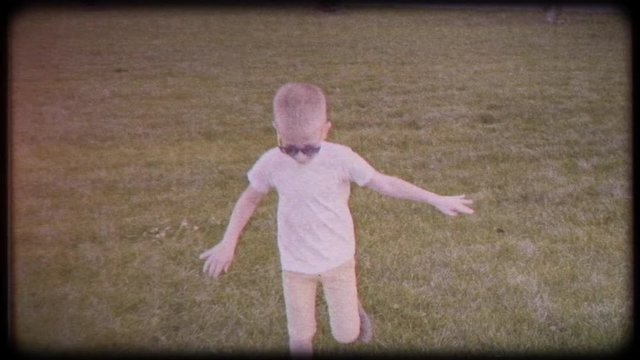 Boy playing soccer ball. Child with the ball runs through the green grass. Family video. Archived video. Old film. Famous footballer in childhood. Children's sport. Family holiday.  Training. Happy