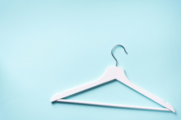 Top view of white clothes hangers on blue background with copy space. Flat lay. Minimalism style. Creative layout. Fashion, store sale, shopping concept. Banner for feminine blog