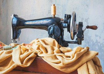 Old sewing machine, fabric and sewing thread in vintage style.