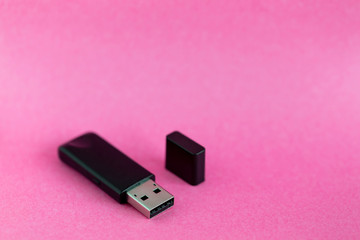 Black USB removable storage device on pink colorful background with copy space for text