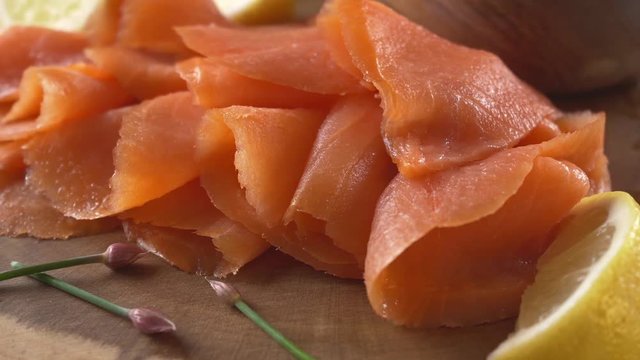 Close-up of sliced smoked salmon with lemon and chives.