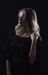 Fototapeta na wymiar Beautiful ,young blonde with bright red lips and expressive eyes in a black jumpsuit. Beauty portrait of a girl. Emotional and bright appearance. Fashion portrait of a woman.