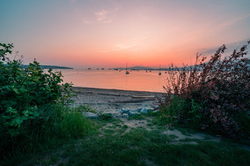 Fototapeta na wymiar Sailboats Watching the Sunset Over a Beach