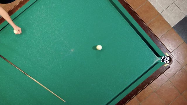 Top view of man playing billiards, hitting the balls with a cue into pockets on a billiard table. 4K