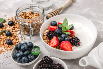 Healthy breakfast with granola, yogurt, fruits, berries on white background.