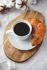 Obraz na płótnie Canvas Cup of black coffee with croissant and milk on table. The concept of breakfast, flat lay, top view.