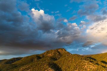 Naklejka premium Światło zachodu słońca podkreśla las sosnowy i jałowcowy oraz szczyt górski pod dramatycznym wieczornym niebem - góry Sangre de Cristo w pobliżu Santa Fe w Nowym Meksyku