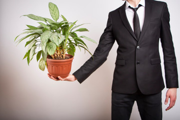  A man in a black jacket with a pot of green plant