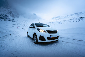Fototapeta premium Car in Norway in front of a mountain in winter - transport