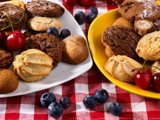 Oatmeal Cookies and sand chocolate cake with blueberries on wooden table in farm style close up. Table setting breakfast for two. Confectionery production.