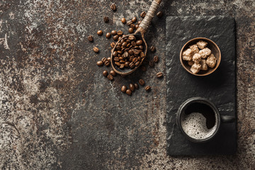 Coffee cup and coffee beans on dark stone background. Top view with copy space. Background with free text space.