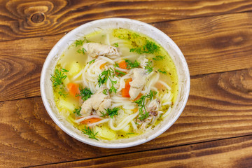 Chicken soup with noodles and vegetables on wooden table