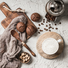 Coffee beans with coffee and muffins on grey textured background.