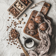 Coffee beans with coffee and muffins on grey textured background.