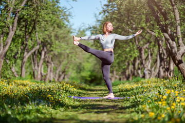 Fototapeta na wymiar Photo of young girl standing on one leg in yoga in forest