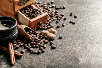 Coffee with coffee grinder and coffee beans on dark textured background.