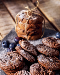 Serving food on slate onto wooden table. Oatmeal cookies biscuit with blueberry on picnic dark tiles countrylike. Chocolate chip cookies tied with string. Bakery products.