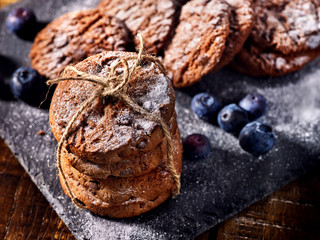 Serving food on slate onto wooden table. Oatmeal cookies biscuit with blueberry on picnic dark tiles countrylike. Chocolate chip cookies tied with string. Bakery products. Beautiful table setting.