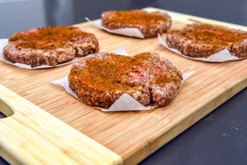 Hamburger patties on wooden cutting board