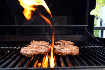 Grilling burgers on a barbecue with flames