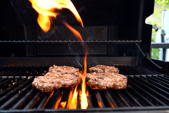 Grilling burgers on a barbecue with flames