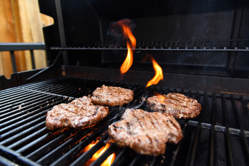 Grilling burgers on a barbecue with flames