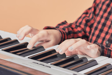 Hard-working Caucusing boy is having is music lesson. He is playing piano. Close-view.