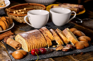 Cookies heart shape, sand rolled biscuit and cinnamon stick on wood table served dessert spoon at kitchen in rustic style. Morning sun flare. Sunlight in kitchen.